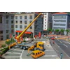 Yellow crane truck parked on urban street with red vehicles and surrounding buildings