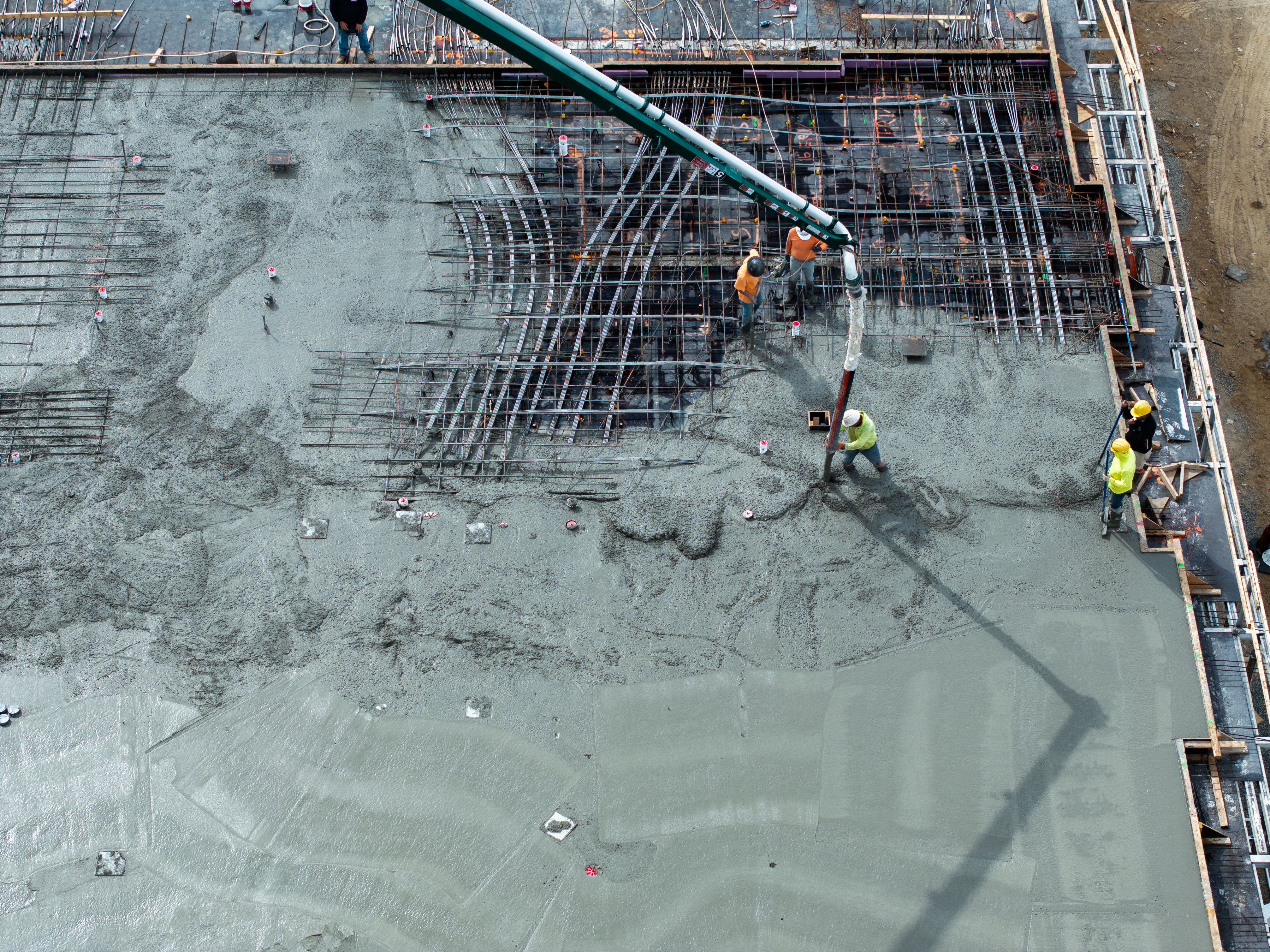 Construction workers pouring concrete on steel rebar foundation using concrete pump