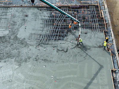 Construction workers pouring concrete on steel rebar foundation using concrete pump