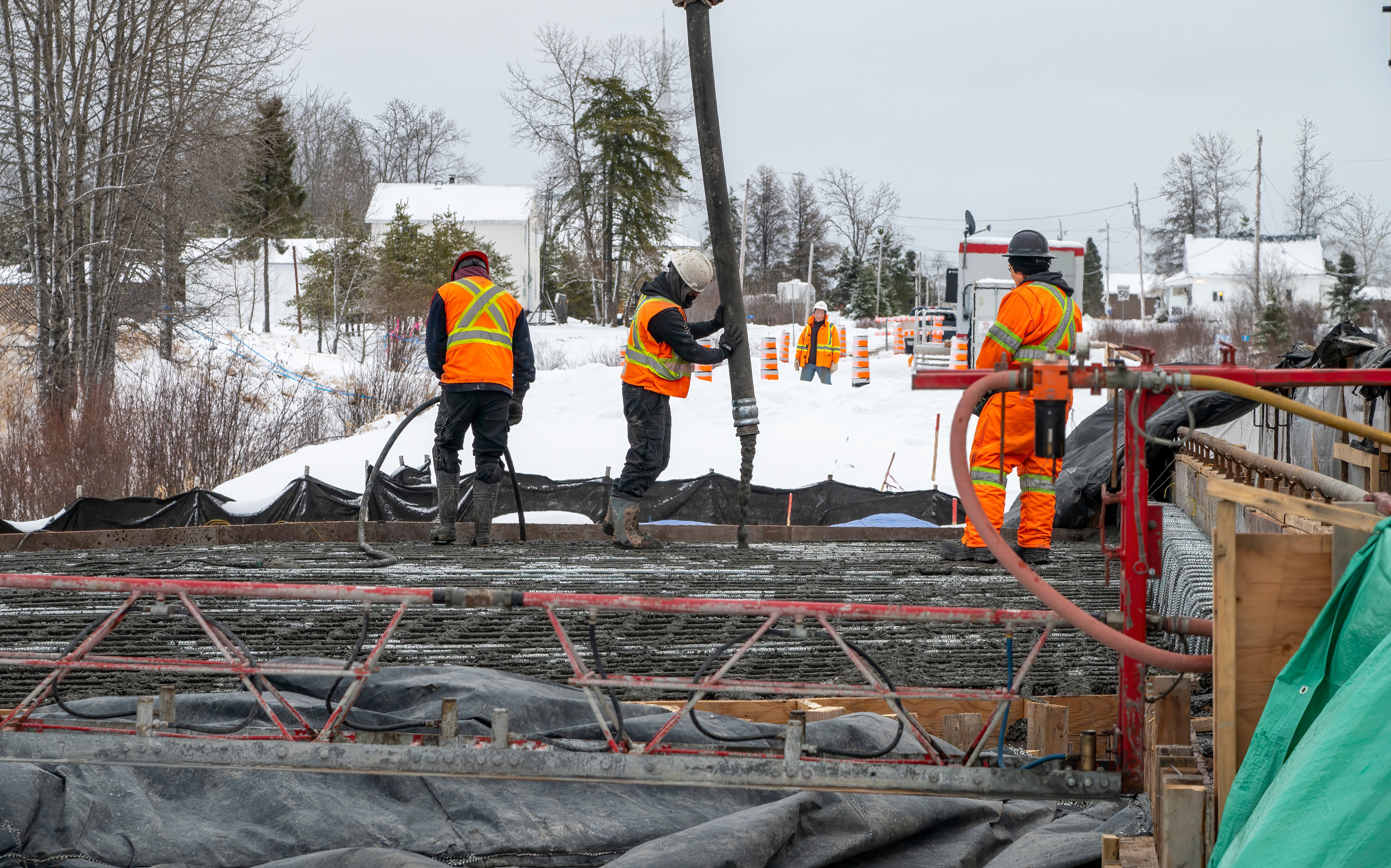 Construction workers in bright safety vests working on winter road project