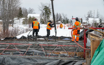 Construction workers in bright safety vests working on winter road project