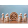 Wooden target icon surrounded by small wooden figurines on blue background