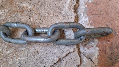 Gray metal chain links connected against weathered stone background