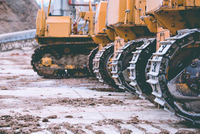 Yellow construction bulldozers with metal tracked wheels on muddy construction site