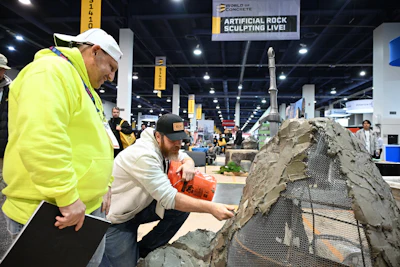 Concrete sculptor working on rock formation at construction industry event