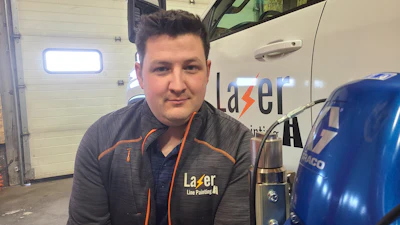 Lazer Line Painting employee in branded gray and orange uniform standing in garage