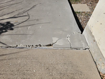 Cracked concrete sidewalk with visible damage and fracture lines