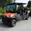 Orange Kubota utility vehicle parked on concrete with trees in background