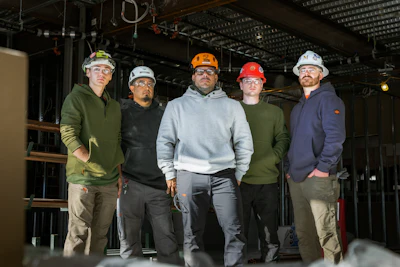 Construction team in hard hats and safety glasses standing in industrial workspace