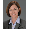 Professional woman in gray blazer smiling with pearl necklace