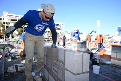 Construction worker laying concrete blocks at an outdoor job site