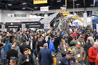 Crowded trade show floor with attendees networking near customer service areas