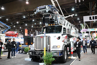 White utility truck with extended crane at industrial trade show exhibition