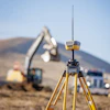 Yellow surveying GPS equipment on tripod at construction site with excavator