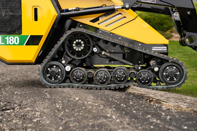 Yellow tracked industrial machine with complex wheel suspension on gravel surface