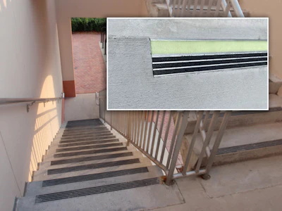 Concrete staircase with metal railings and black safety traction strips