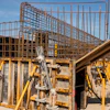 Construction site with steel rebar frames and yellow scaffolding supports