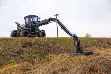 Green and black forestry harvester machine extending long mechanical arm across grassy field