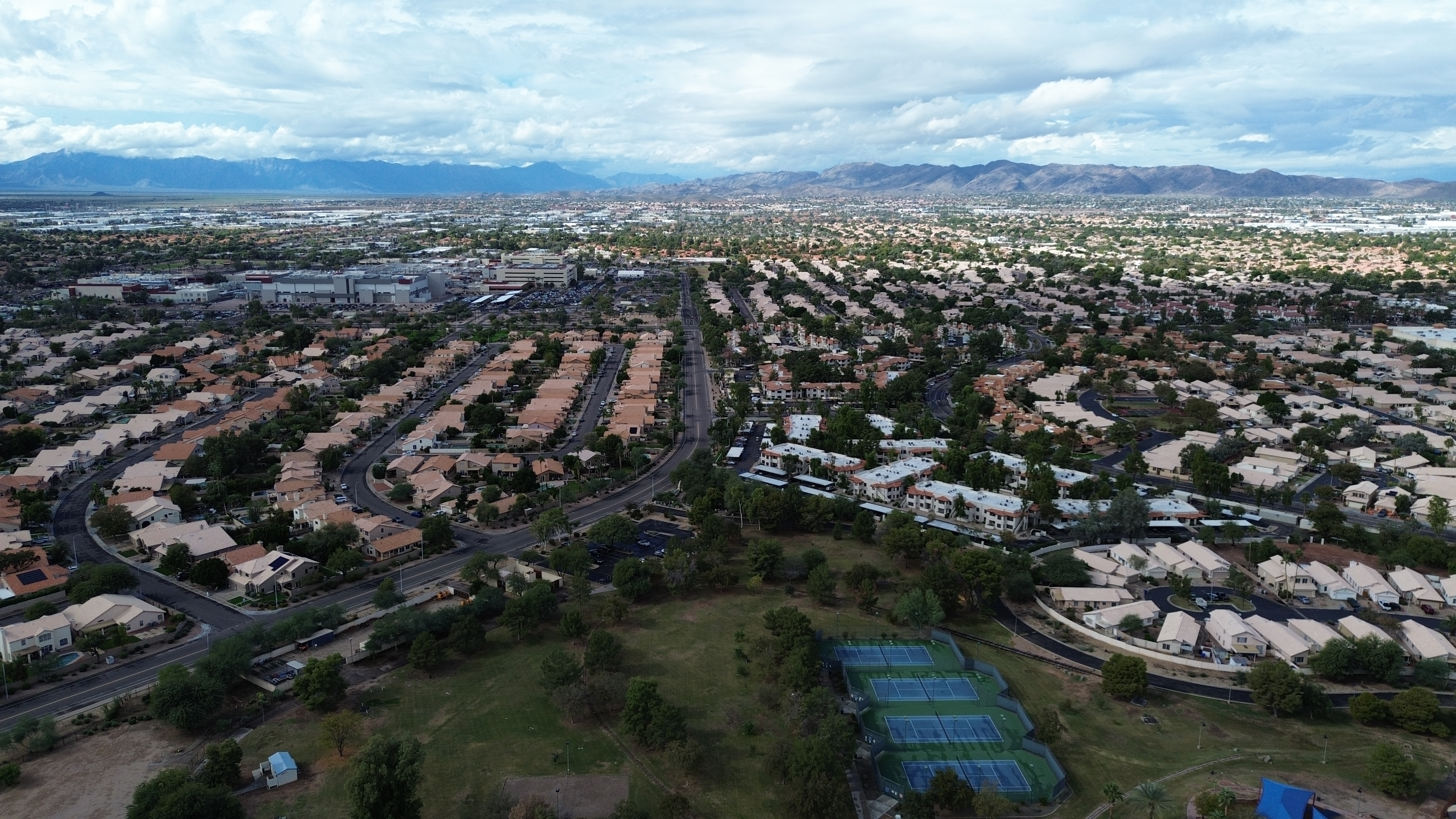Aerial view of suburban neighborhood with curved streets and mountain range in distance