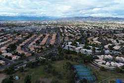 Aerial view of suburban neighborhood with curved streets and mountain range in distance