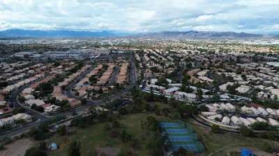 Aerial view of suburban neighborhood with curved streets and mountain range in distance