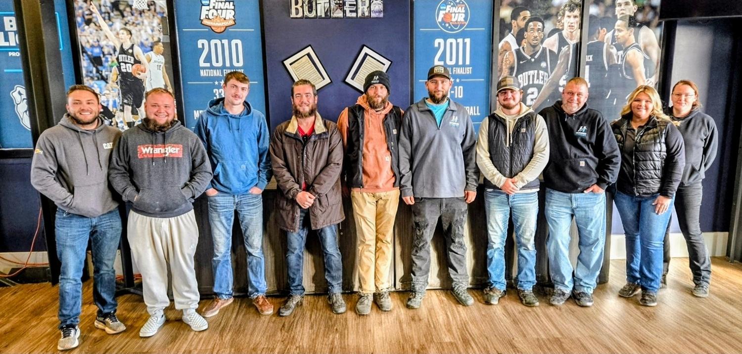 Group of ten people standing together in front of sports team year posters