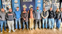 Group of ten people standing together in front of sports team year posters