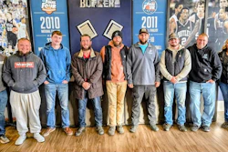 Group of ten people standing together in front of sports team year posters