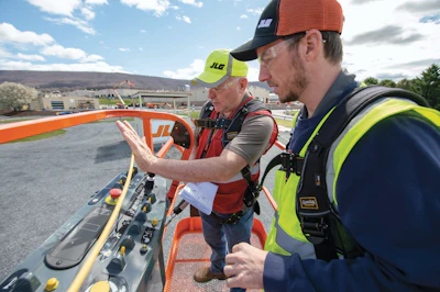Construction workers operating lift controls on elevated work platform outdoors