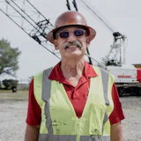 Mature construction worker in safety vest and hard hat near industrial equipment