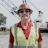 Mature construction worker in safety vest and hard hat near industrial equipment Headshot