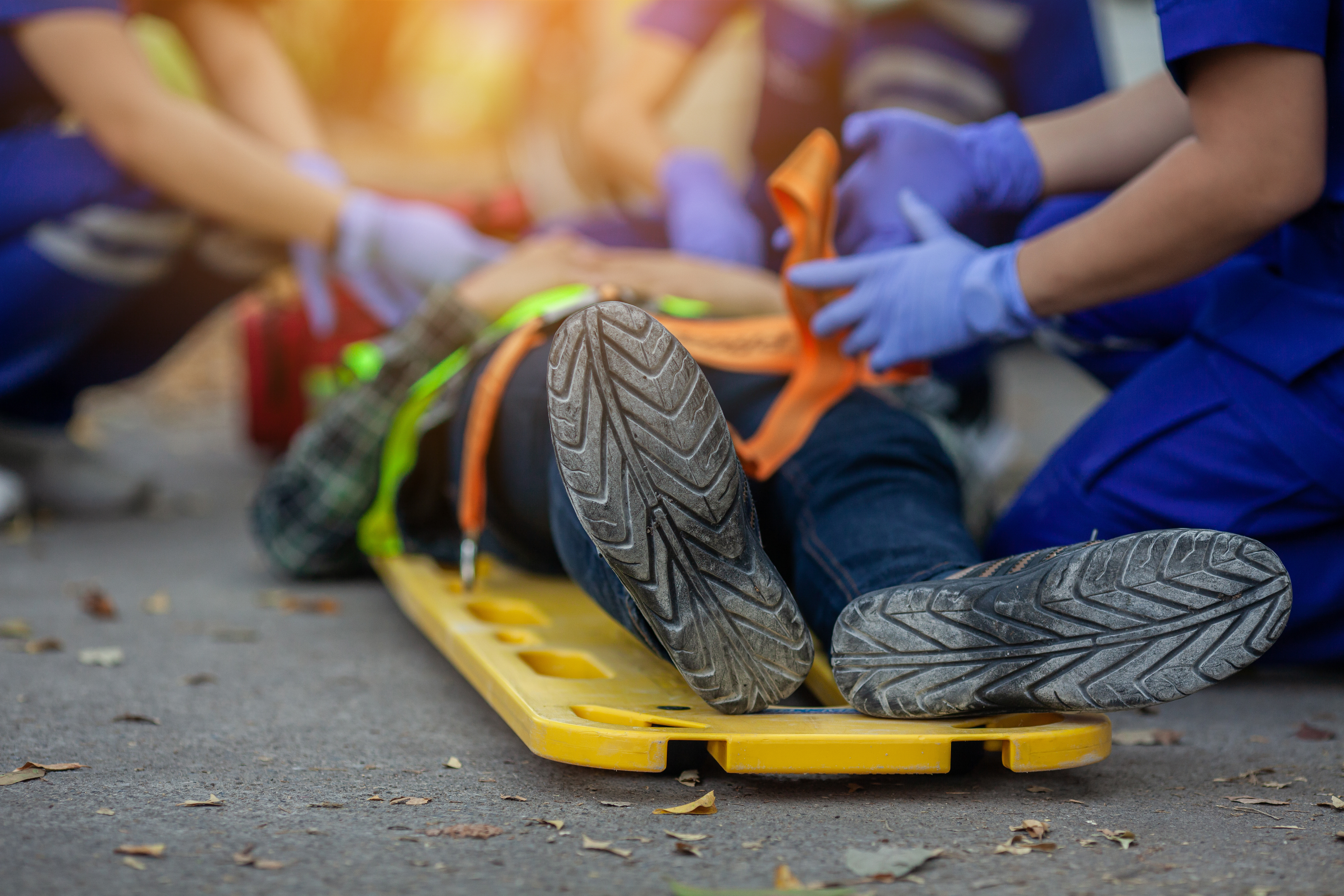 Emergency medical team treating patient on yellow stretcher with protective gloves