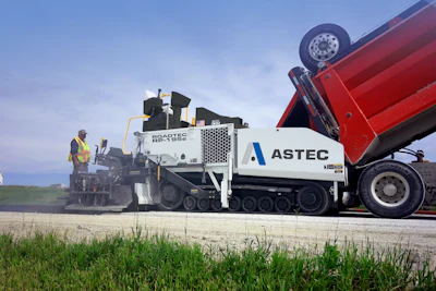 Astec road paving machine with red dump truck on construction site