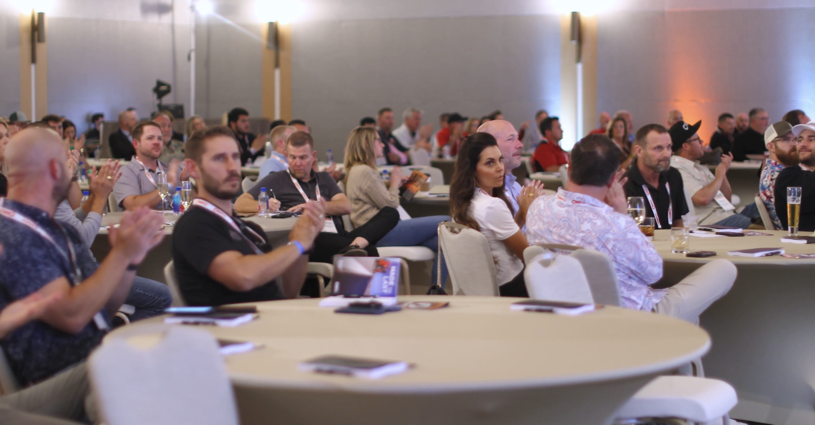 Conference attendees gathered at round tables in a professional meeting space