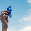 Blue awareness ribbon raised against cloudy blue sky