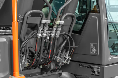Hydraulic hoses and metal connectors inside industrial machinery interior