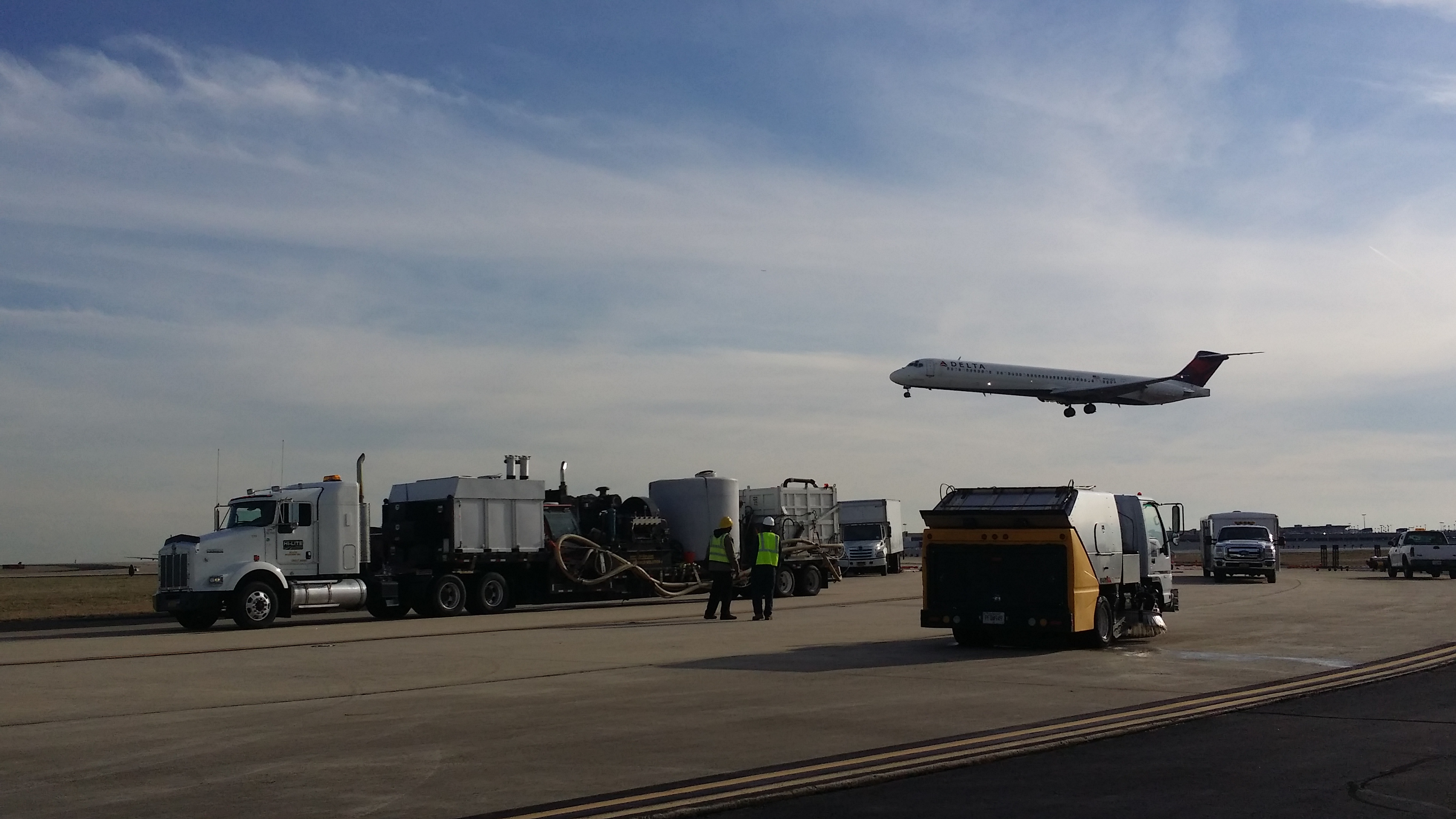Airport tarmac with ground service vehicles and commercial airplane taking off
