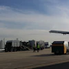 Airport tarmac with ground service vehicles and commercial airplane taking off