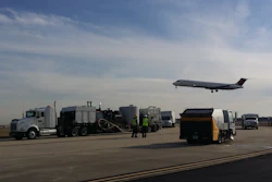 Airport tarmac with ground service vehicles and commercial airplane taking off
