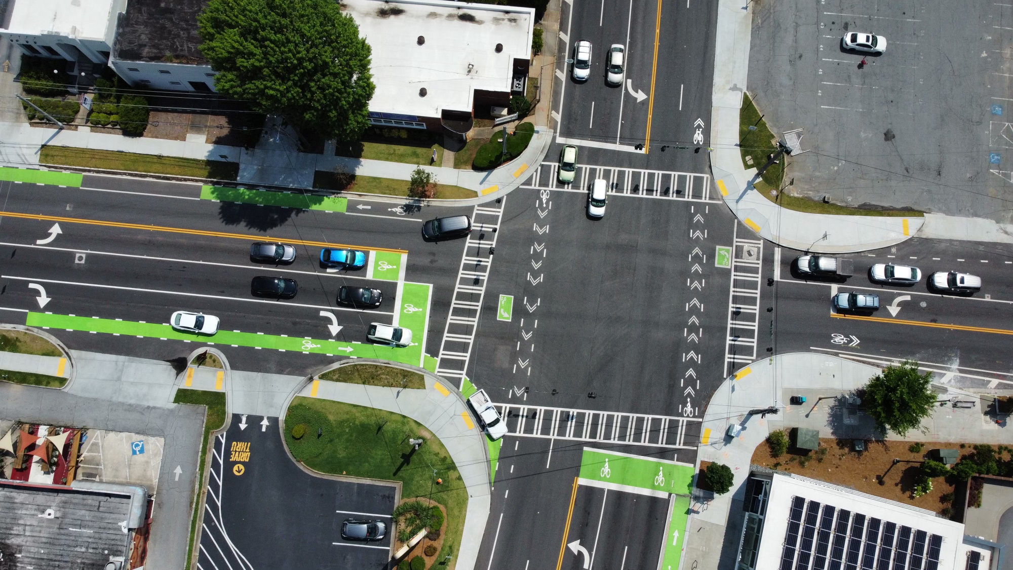 Aerial view of urban intersection with traffic lanes, crosswalks, and green bicycle paths