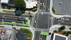 Aerial view of urban intersection with traffic lanes, crosswalks, and green bicycle paths