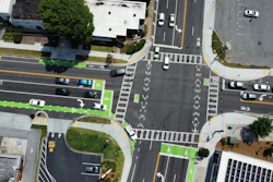 Aerial view of urban intersection with traffic lanes, crosswalks, and green bicycle paths