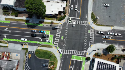 Aerial view of urban intersection with traffic lanes, crosswalks, and green bicycle paths