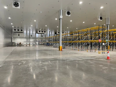 Empty cold storage warehouse with yellow industrial shelving and overhead ventilation