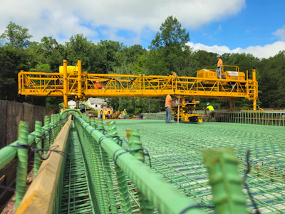 Yellow construction crane positioned over green steel reinforcement grid at infrastructure project site