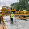 Yellow concrete paving machine on construction site with workers in safety vests