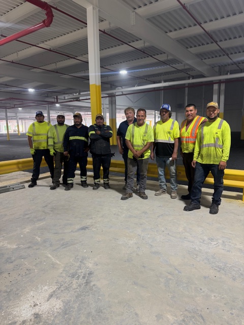 Construction team in high-visibility safety vests standing in industrial warehouse space