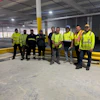 Construction team in high-visibility safety vests standing in industrial warehouse space
