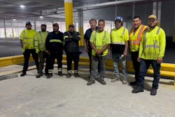 Construction team in high-visibility safety vests standing in industrial warehouse space