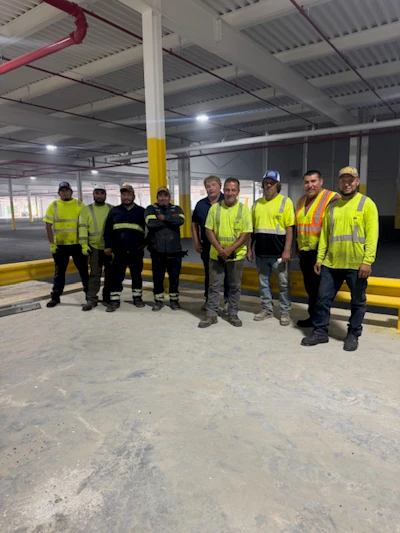 Construction team in high-visibility safety vests standing in industrial warehouse space